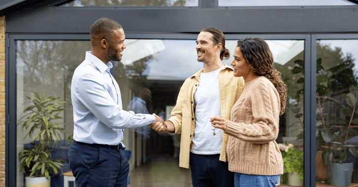 Real estate agent handshaking with a couple after buying a house