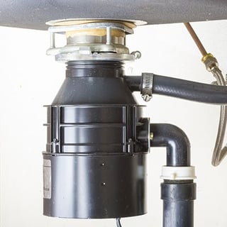 A garbage disposal mounted under the kitchen sink.