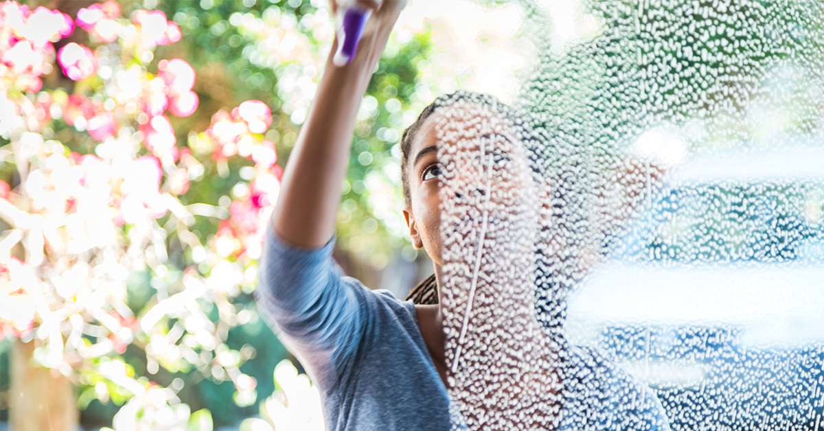 Young woman washing window